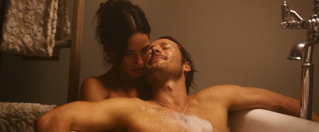 ‘Hit Man’ Star Adria Arjona Says She and Glen Powell Shot Their Sex Scenes ‘With a Crazy Rash’: ‘How Much Makeup Do You Have on Your Ass?’